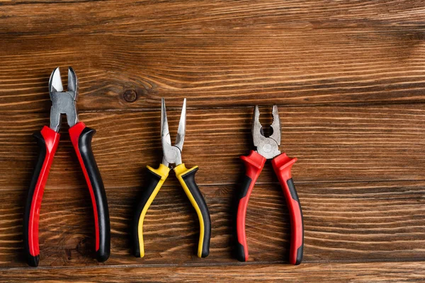 Top view of pliers and wire cutters on wooden surface, labor day concept — Stock Photo