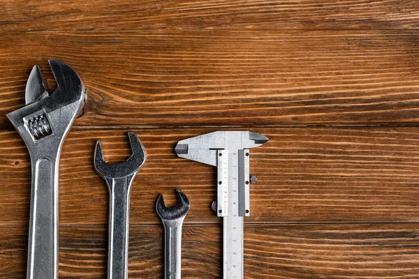 Top view of different wrenches and calipers on wooden table, labor day concept — Stock Photo