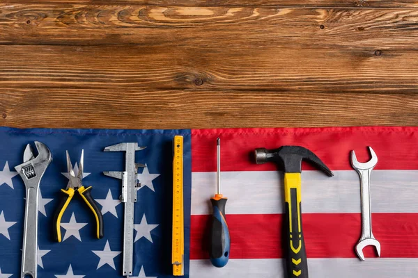 Верхний вид различных инструментов и флаг США на деревянном столе, концепция трудового дня — стоковое фото