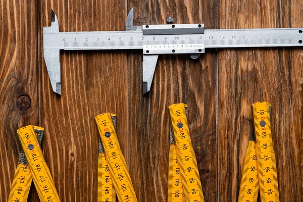 Vue de dessus de la règle pliante et des étriers sur la surface en bois, concept de jour de travail — Photo de stock