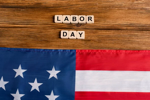 Vue du dessus du drapeau des Etats-Unis près de cubes avec lettrage de la journée de travail sur une table en bois — Photo de stock