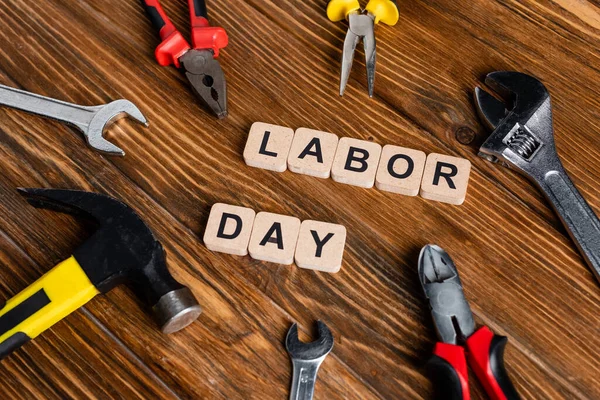 Different tools and cubes with labor day lettering on wooden surface — Stock Photo