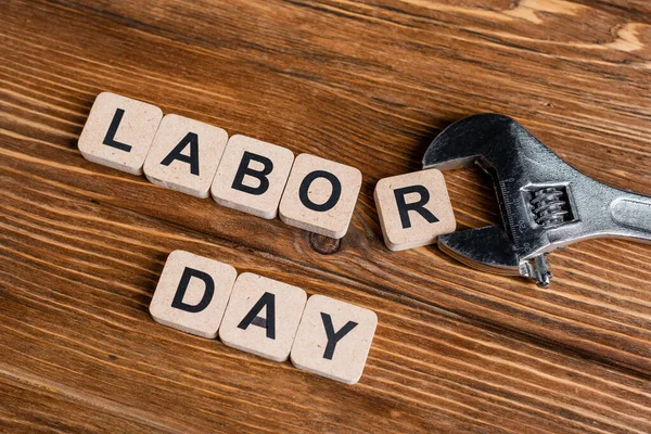 Top view of wrench near cubes with labor day lettering on wooden table — Stock Photo