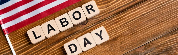 Top view of cubes with labor day lettering near small american flag on wooden table, banner — Stock Photo