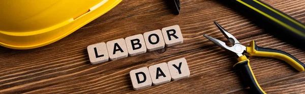 Top view of pliers near helmet and cubes with labor day lettering, banner — Stock Photo