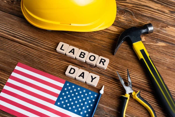 Usa flag, hammer, pliers, hardhat and cubes with labor day lettering on wooden table — Stock Photo