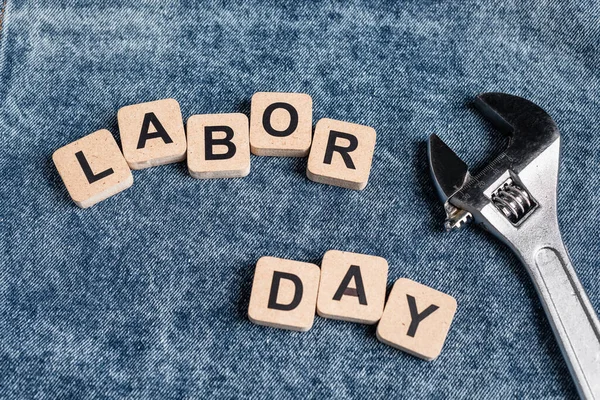 Top view of cubes with labor day lettering near wrench on denim clothes — Stock Photo