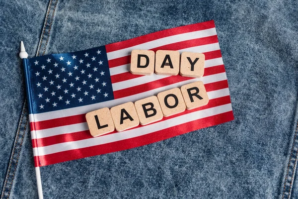 Vista superior da pequena bandeira dos EUA e cubos com letras do dia de trabalho em pano de ganga azul — Fotografia de Stock