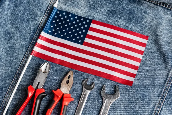 Draufsicht auf kleine US-Flagge auf blauem Jeanstuch in der Nähe diverser Werkzeuge, Arbeitszeitkonzept — Stockfoto