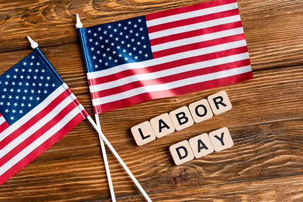 Vista dall'alto di cubi con scritte giorno del lavoro vicino a piccole bandiere americane su superficie di legno — Foto stock