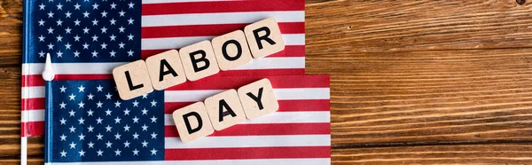 Vista dall'alto di piccole bandiere USA vicino a cubi con scritte per il giorno del lavoro su superficie di legno, banner — Foto stock