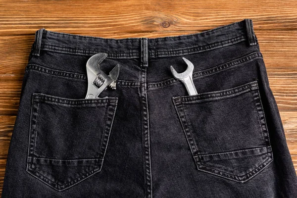 Top view of wrenches in back pockets of jeans in wooden surface, labor day concept — Stock Photo