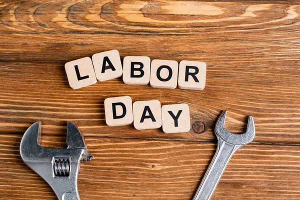 Top view of wrenches near cubes with labor day lettering on wooden table — Stock Photo