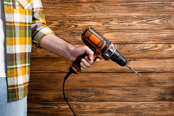 Vue recadrée de l'ouvrier avec perceuse électrique près du mur en bois, concept de la journée de travail — Photo de stock