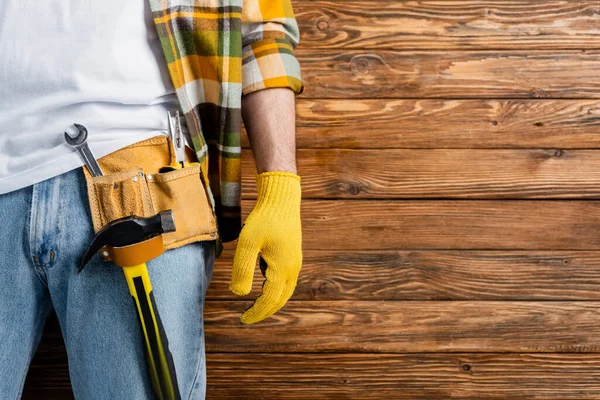 Vista ritagliata di tuttofare in cintura strumento e guanto da lavoro su sfondo di legno, concetto di giornata di lavoro — Foto stock