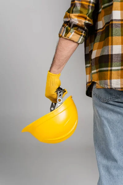 Vista posterior del trabajador recortado sosteniendo hardhat aislado en gris, concepto del día del trabajo - foto de stock