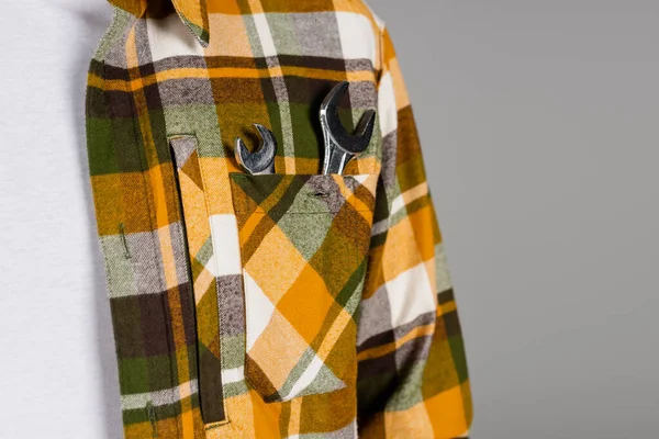 Cropped view of foreman with wrenches in pocket of plaid shirt isolated on grey, labor day concept — Stock Photo