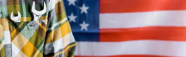 Vue partielle de l'ouvrier en chemise à carreaux avec des clés dans la poche près du drapeau des Etats-Unis sur fond flou, concept de la journée de travail, bannière — Photo de stock