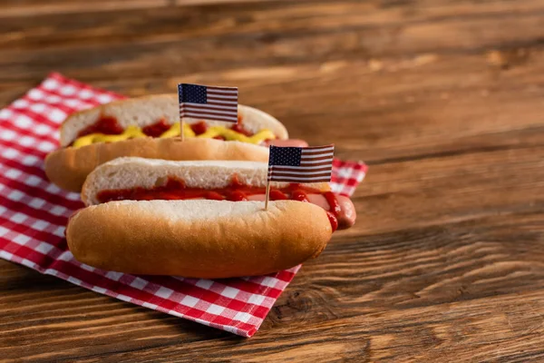 Tasty hot dogs with small usa flags on wooden surface — Stock Photo