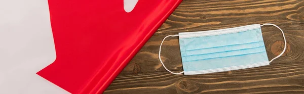 Top view of canadian flag and medical mask on wooden surface, banner — Stock Photo