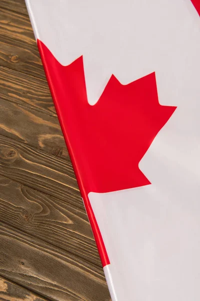 Vista superior de la bandera canadiense con hoja de arce rojo en la superficie de madera - foto de stock