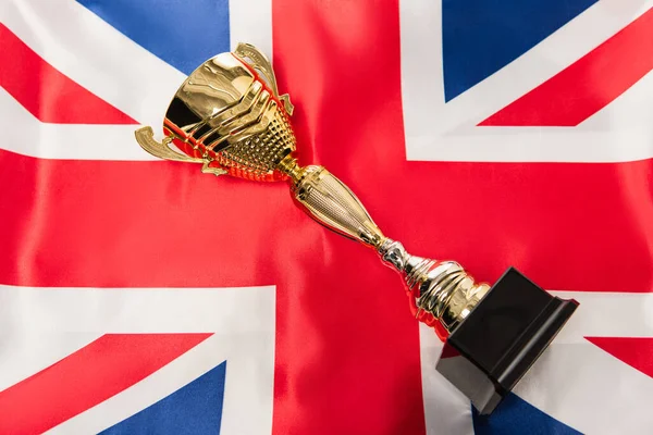 Top view of golden trophy near national flag of united kingdom with red cross — Stock Photo