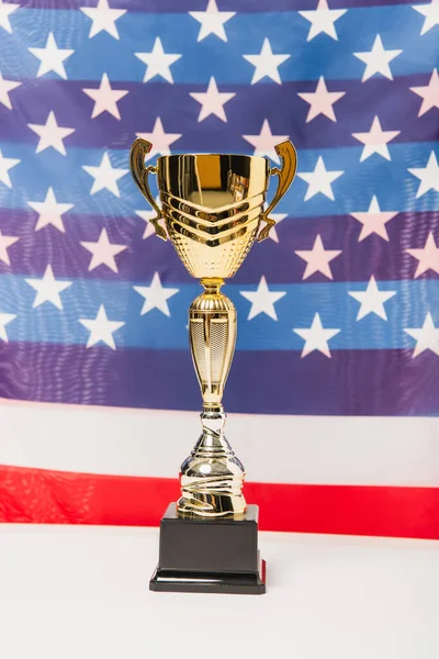 Copa dorada con estrellas y rayas de bandera americana sobre fondo borroso - foto de stock