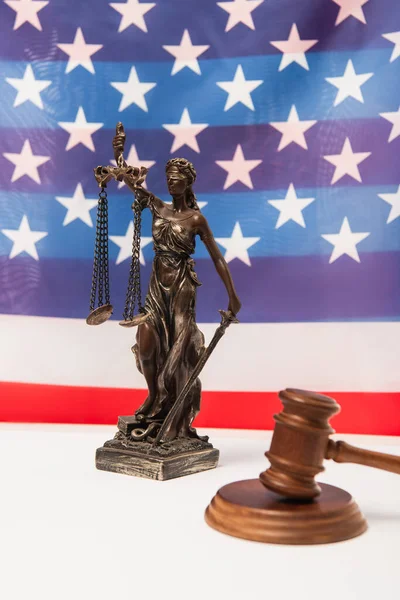 Wooden gavel and statuette of justice near american flag on background — Stock Photo