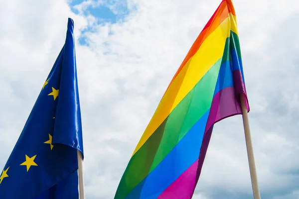 Banderas americanas y lgbt contra el cielo azul con nubes - foto de stock