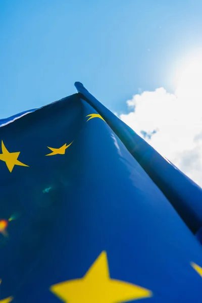 Vista in basso della bandiera blu dell'Unione europea contro il cielo con le nuvole — Foto stock