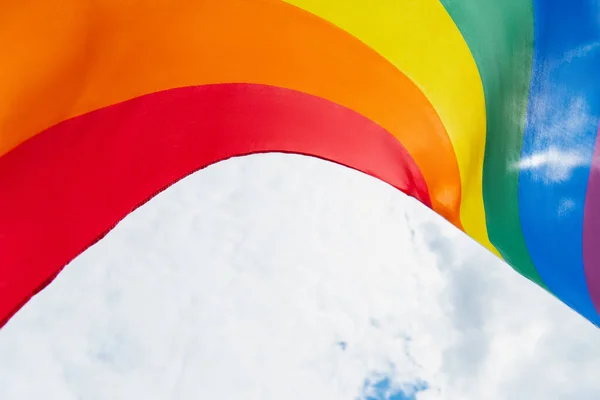 Vista inferior da bandeira lgbt colorido contra o céu nublado — Fotografia de Stock