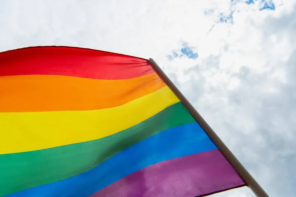 Vista de ángulo bajo de la bandera lgbt colorido contra el cielo nublado - foto de stock