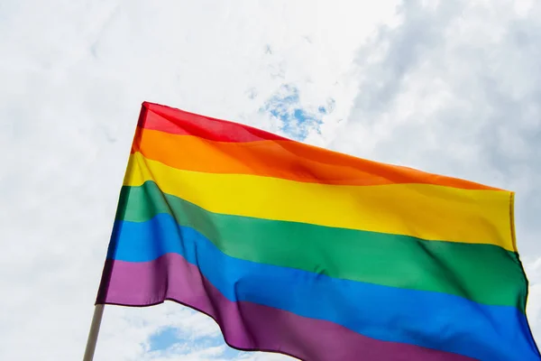 Baixo ângulo de visão da bandeira lgbt colorido contra o céu com nuvens — Fotografia de Stock