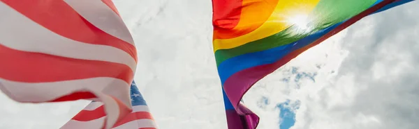 Bottom view of american and colorful lgbt flags against sky, banner — Stock Photo