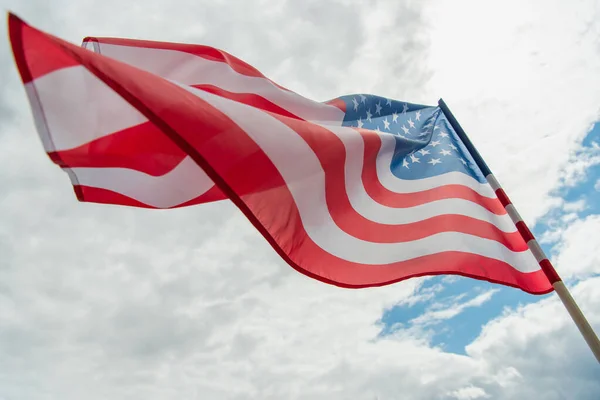 Vista de ángulo bajo de la bandera americana con estrellas y rayas ondeando contra el cielo nublado - foto de stock
