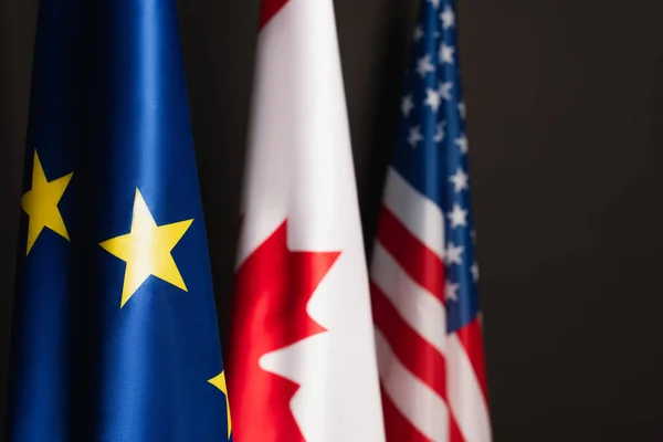 Banderas europeas azules, canadienses y americanas aisladas sobre negro - foto de stock