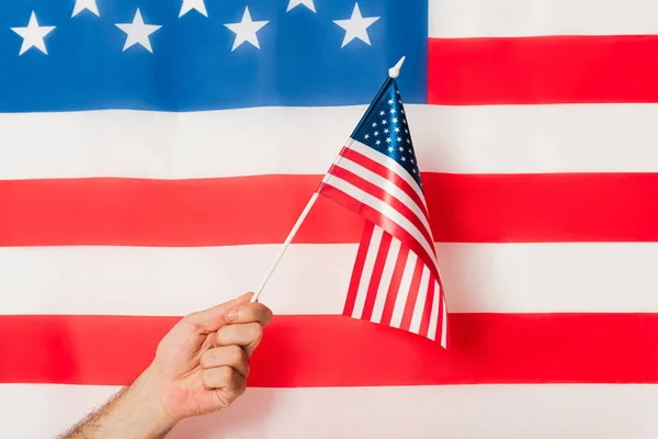 Vista recortada del hombre patriótico sosteniendo la bandera de América contra el símbolo americano - foto de stock