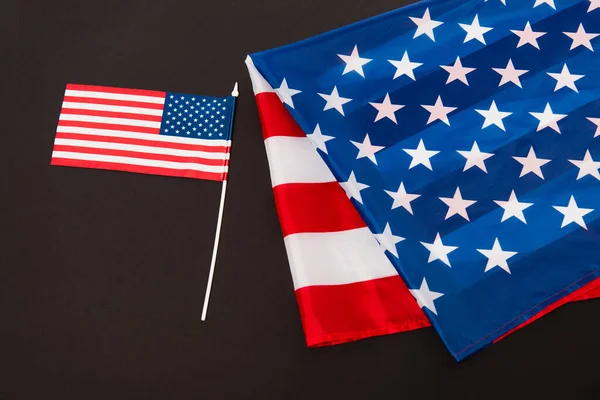 Маленький американський прапор біля тканини з зірками і смугами ізольовані на чорному — стокове фото