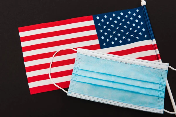 Hochwinkelaufnahme der blauen medizinischen Maske auf amerikanischer Flagge isoliert auf schwarz — Stockfoto