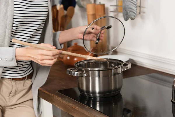 Abgeschnittene Ansicht einer Frau mit Kochlöffel und Deckel beim Kochen in der Küche — Stockfoto