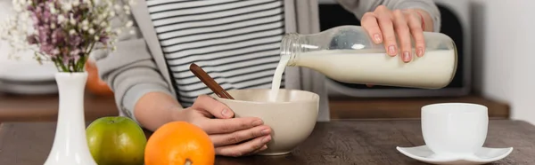Частичный вид женщины, наливающей молоко в миску, баннер — стоковое фото