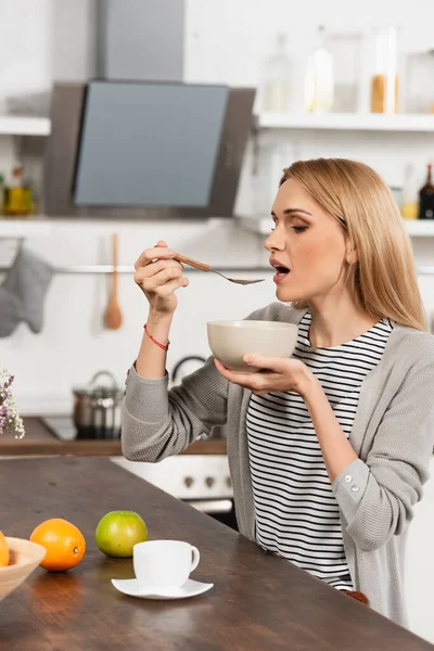 Blonde woman eating breakfast in kitchen — Stock Photo