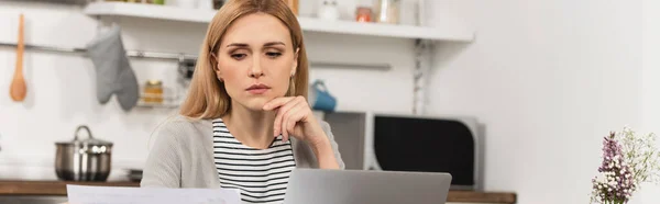 Pensive freelancer looking at paper near laptop, banner — Stock Photo