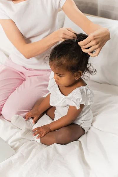Mãe amarrando o cabelo da criança americana africana adotada na cama — Fotografia de Stock