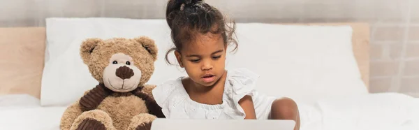Afro-américain enfant regarder film sur ordinateur portable près de peluche, bannière — Photo de stock