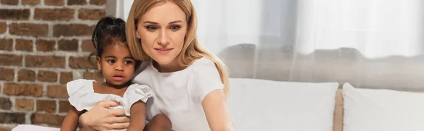 Fröhliche Mutter und adoptierte Afroamerikanerin schaut im Schlafzimmer weg, Banner — Stockfoto