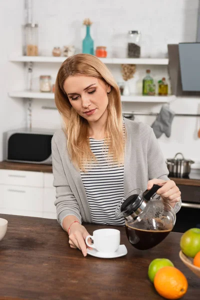 Mulher loira derramando café na xícara do pote — Fotografia de Stock