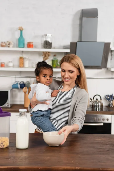 Happy mother holding adopted african american kid with spoon — Stock Photo