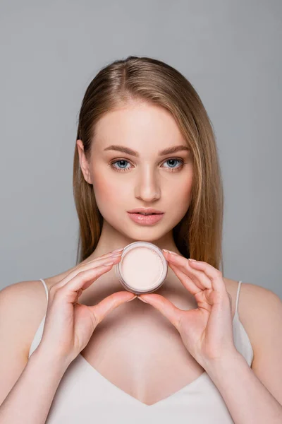 Pretty young woman holding container with face powder isolated on grey — Stock Photo
