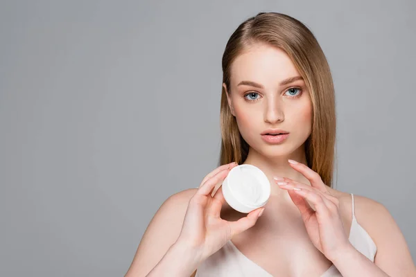 Bonita mujer sosteniendo contenedor con polvo facial aislado en gris — Stock Photo